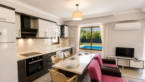 Une cuisine moderne avec un coin repas, un téléviseur et une vue sur une piscine.