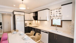 Une cuisine moderne avec un coin repas, un réfrigérateur, un lave-vaisselle et une fenêtre donnant sur le paysage urbain.