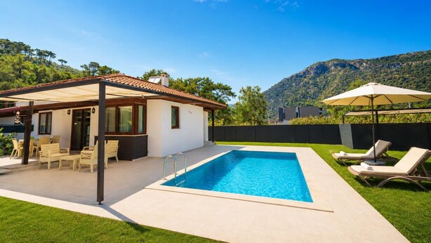 Une maison moderne dotée d’une piscine, d’un espace salon extérieur et offrant une vue sur les montagnes.