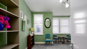Een kamer met groene wanden, witte sierlijsten, een blauwe stoel, een tafeltje en een lamp.