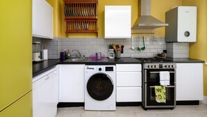 Een compacte keuken met een wasmachine, oven en een inbouwfornuis.
