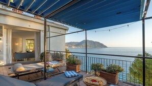 A terrace with outdoor seating, a table with drinks, and a view of the sea. - Casa Chiara 6+2, Emma Villas (Sori)