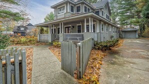 Ein zweistöckiges Haus mit Veranda, Garage und einem umzäunten Einfahrtsweg.