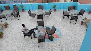A rooftop patio with outdoor seating and a person using a laptop. - Fort view palace (Jodhpur)