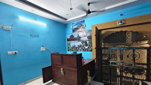A reception area with a blue wall, a wooden desk, a ceiling fan, and a decorative gate. - Fort view palace (Jodhpur)