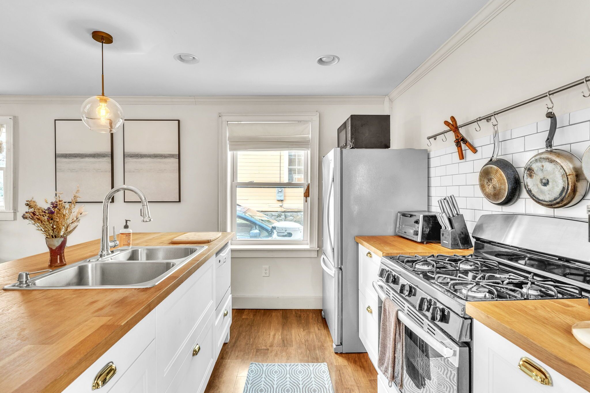 A modern kitchen with a central island, stainless steel appliances, and a view to the outside.