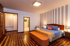 A hotel room with a bed, a bench, a nightstand, a lamp, a door, and a patterned floor. - 4bdrs, Balcony w/ Sea View, and Garagea 3730/201 (Rio de Janeiro)