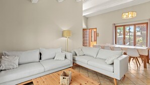 Una sala de estar con dos sofás, una lámpara y un comedor con mesa y sillas.