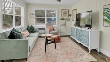 A living room with a sofa, a coffee table, a television, and a cabinet.