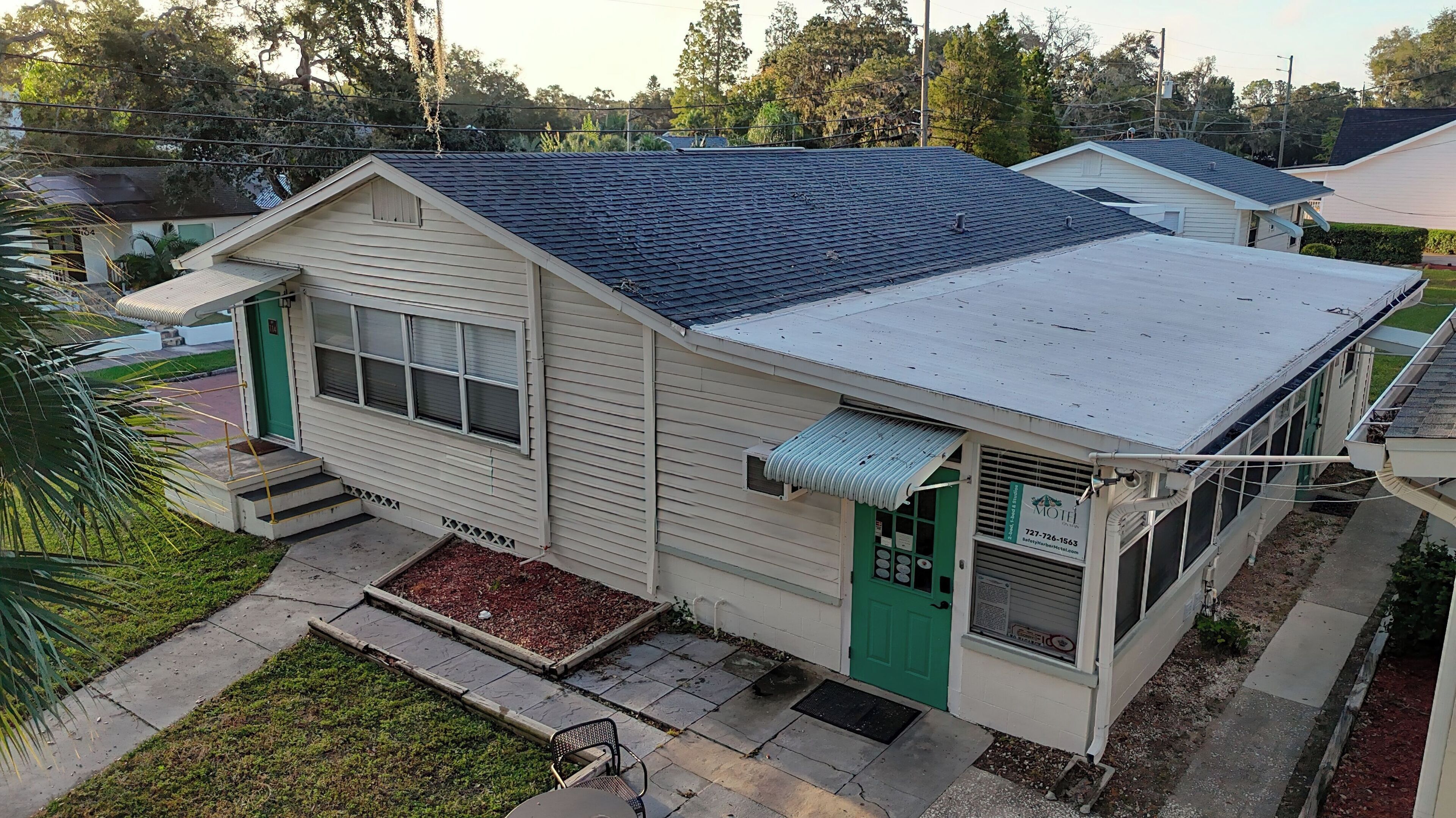 A two-story motel with a flat roof, a green door, and a small porch area.