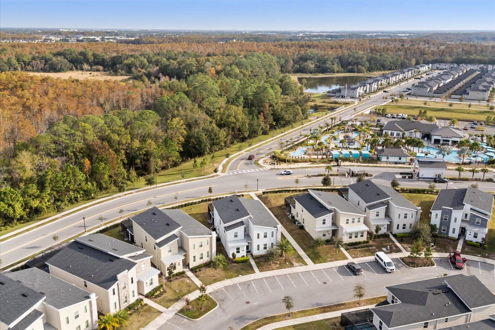 A residential area with modern houses, a road, and a body of water in the background.