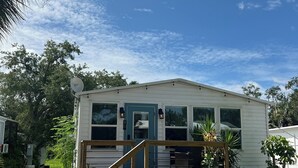 Ein eingeschossiges Haus mit Veranda, einer kleinen Terrasse und einem Eingang.