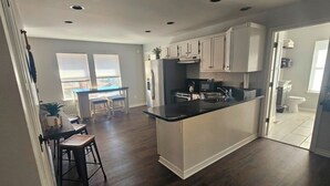 Een moderne keuken met een centraal eiland, witte kasten en een donker aanrecht.