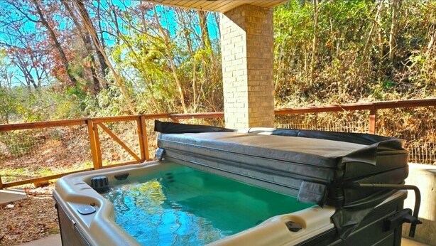 Een jacuzzi met een houten terras en een bakstenen muur op de achtergrond.