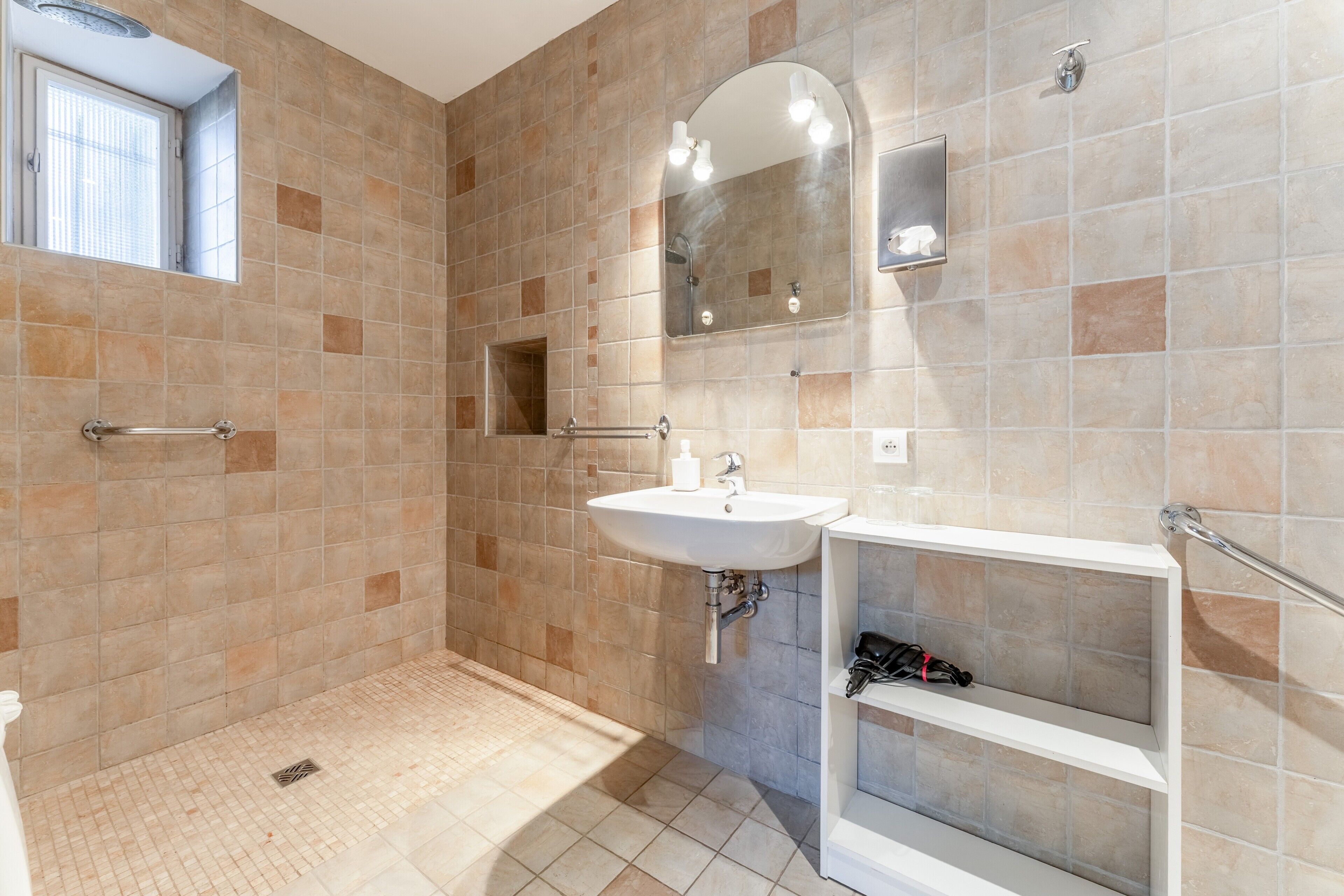 Une salle de bain avec une douche, un lavabo et un miroir.
