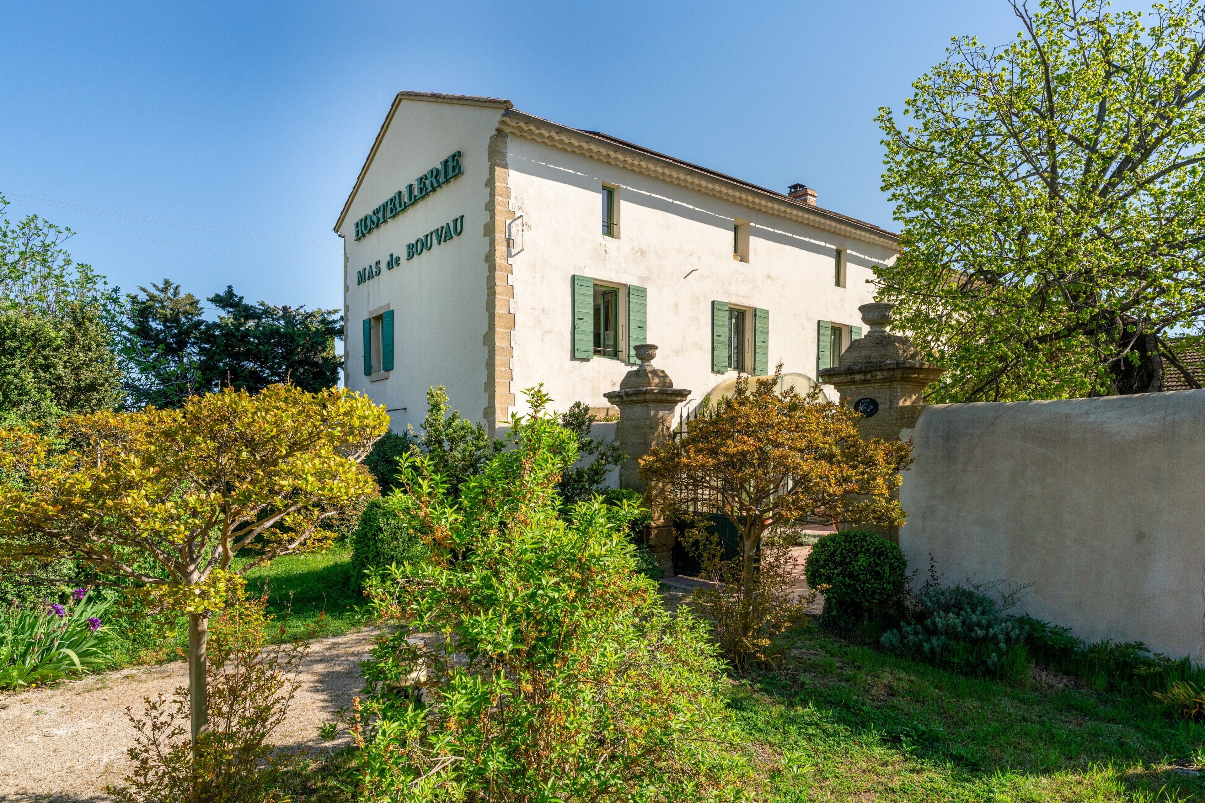 A building with a sign reading 'HUNTERIE MAS de BOUVAU' surrounded by greenery and a stone wall.