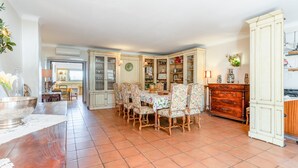A dining area with a table set for six, surrounded by patterned chairs, and a wooden cabinet with drawers.