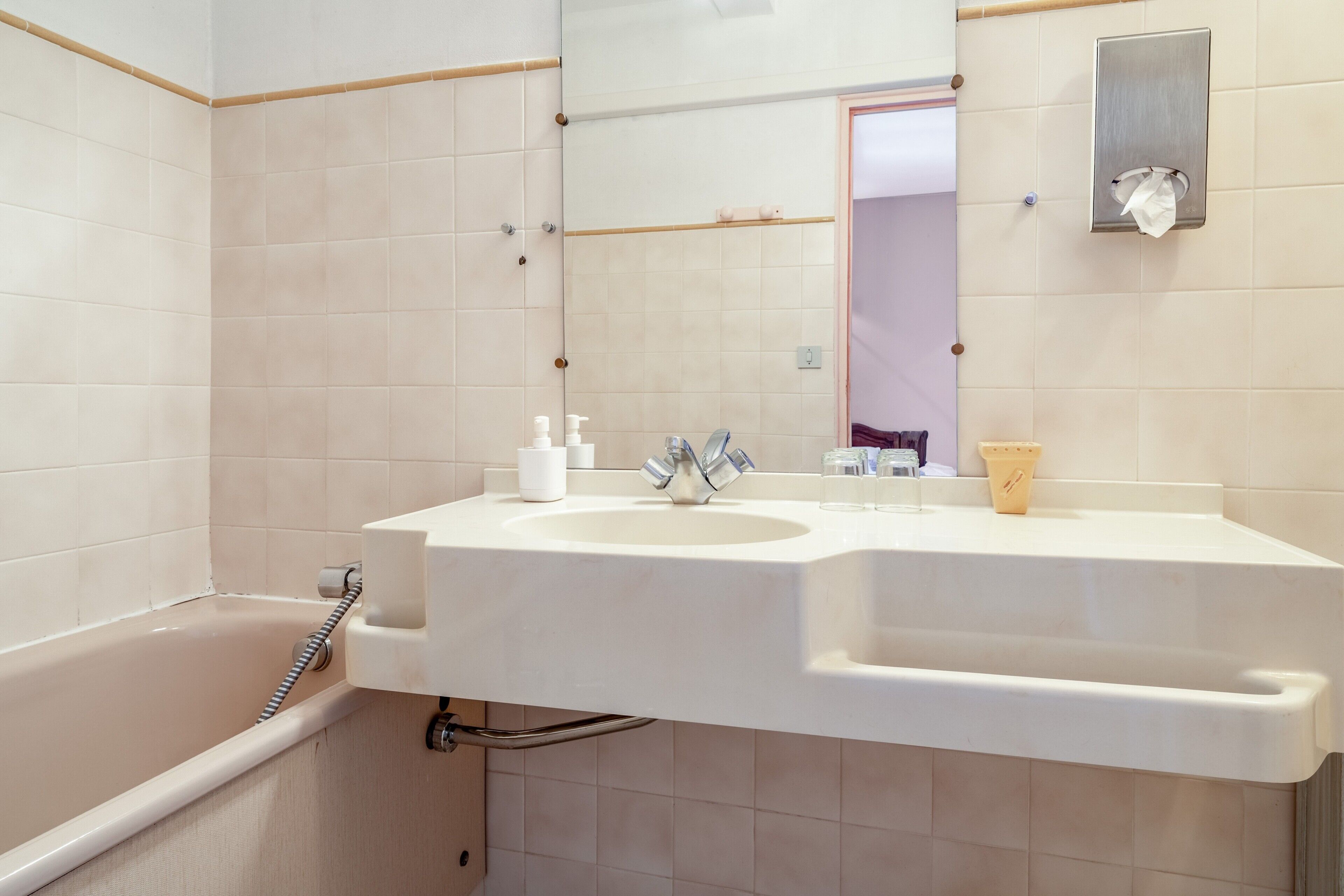 A bathroom with a white sink, mirror, and bathtub.