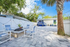 A patio area with outdoor furniture, a small building, and a palm tree.
