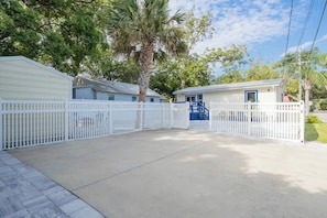 A gated residential area with a concrete driveway leading to a single-story house with a blue door. - La Casita – A Family-Friendly 2-Bedroom Vacation Rental in Historic West Au... (St. Augustine)
