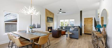 A spacious living area with a dining table, chairs, a sofa, and a fireplace.