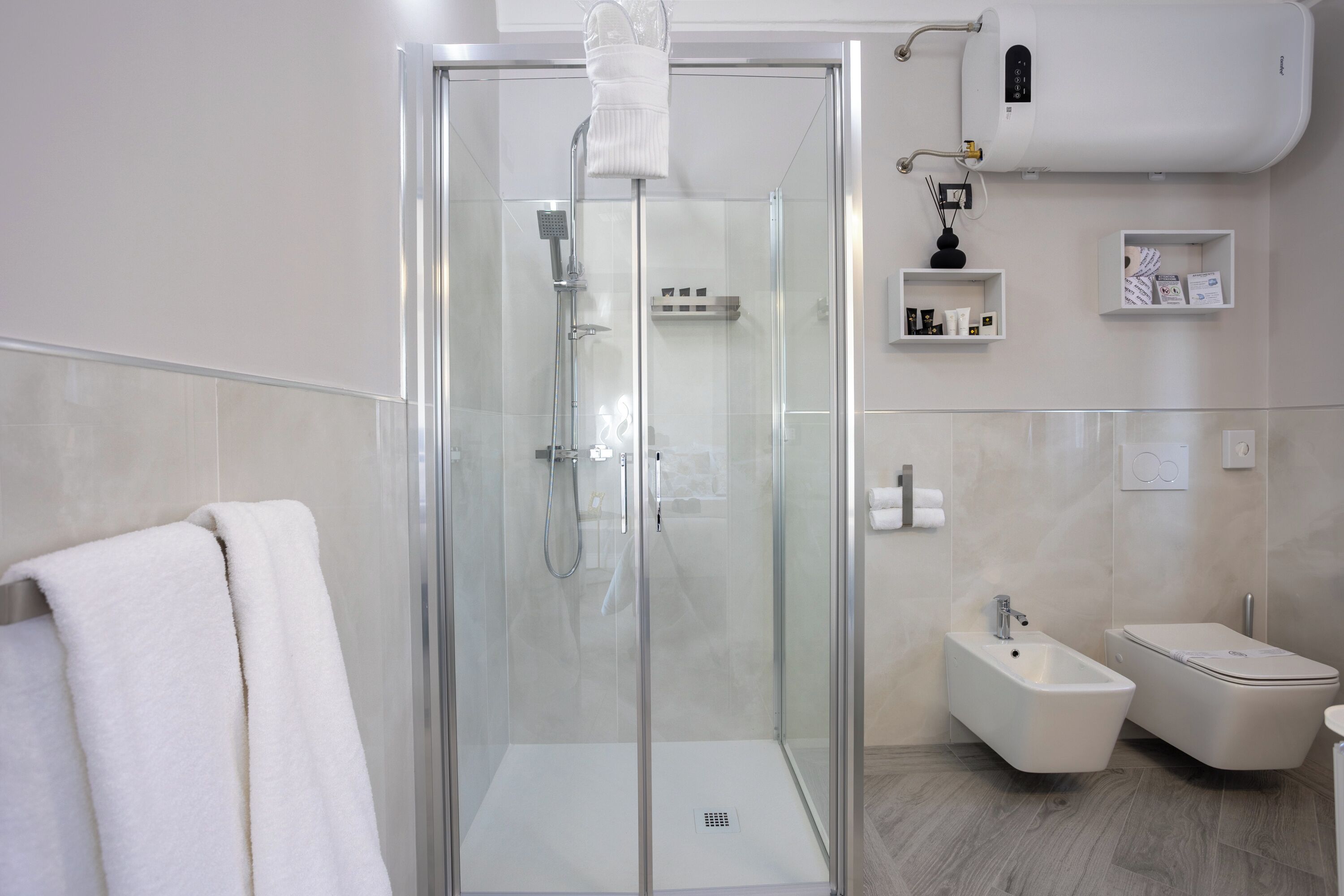 A modern bathroom with a glass-enclosed shower, a bidet, and a toilet.