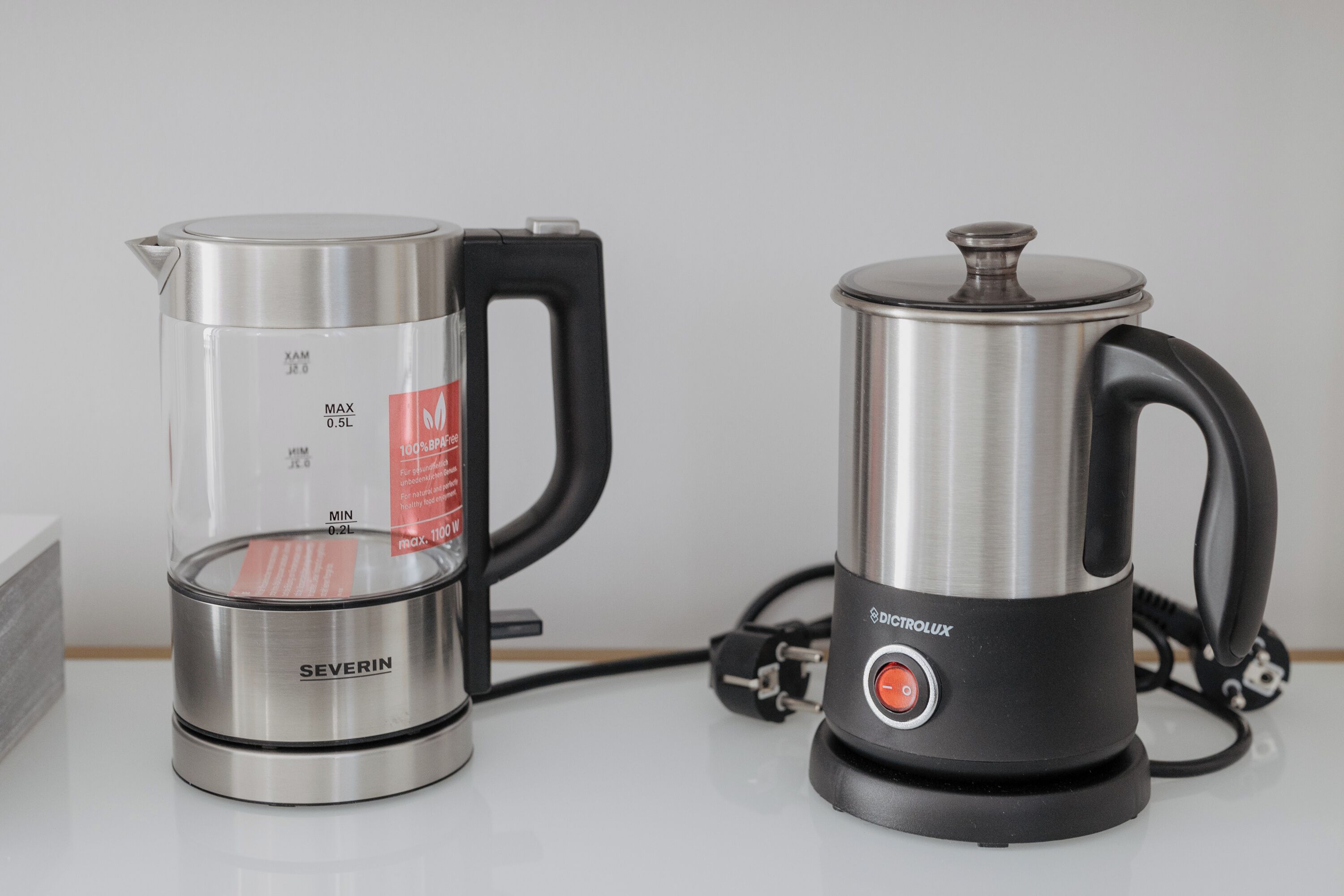 Two electric kettles, one labeled SEVERIN and the other DICTROLUX, placed on a white surface.