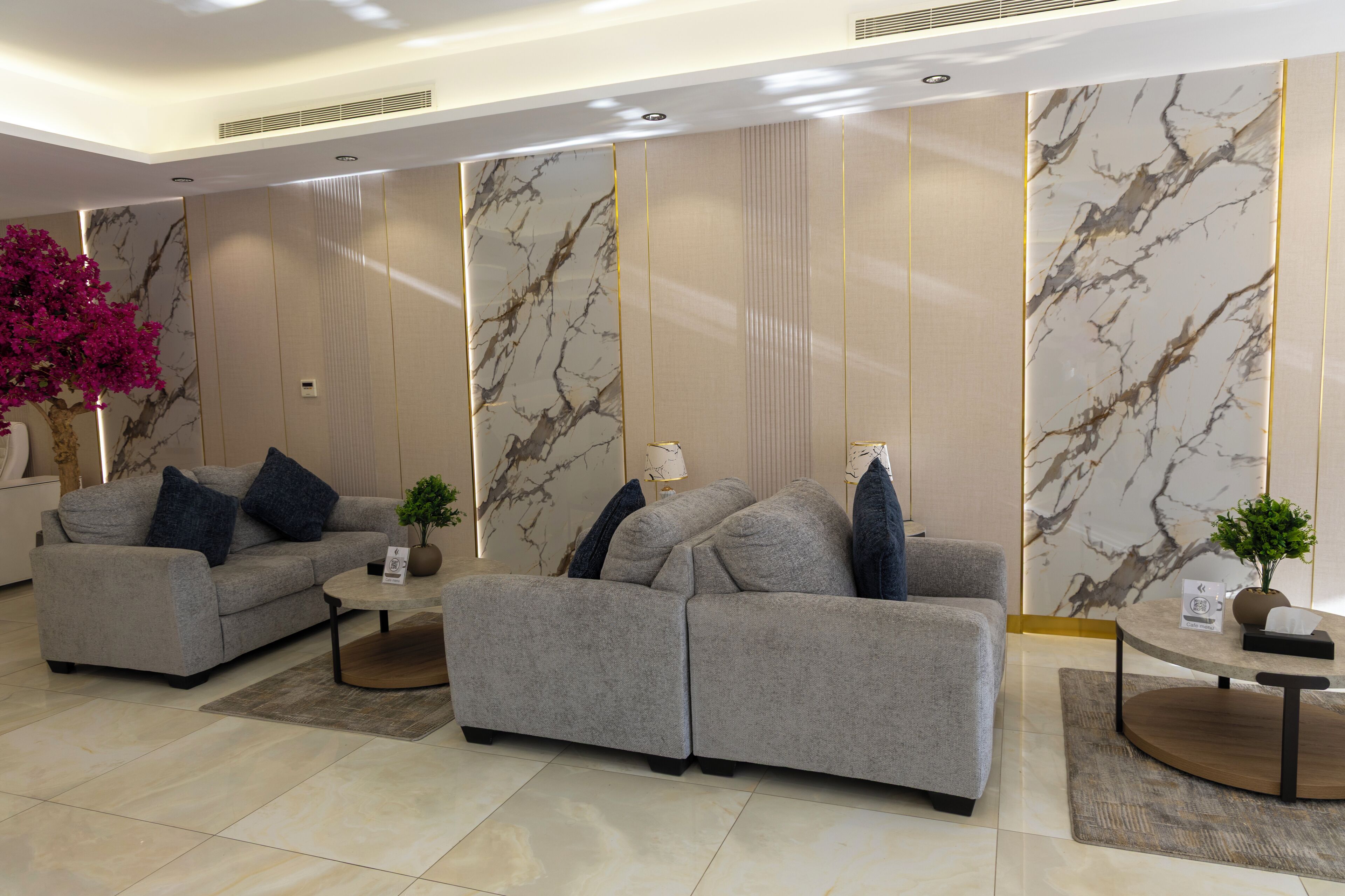 Un salón moderno con dos sofás grises, una mesita y plantas decorativas.