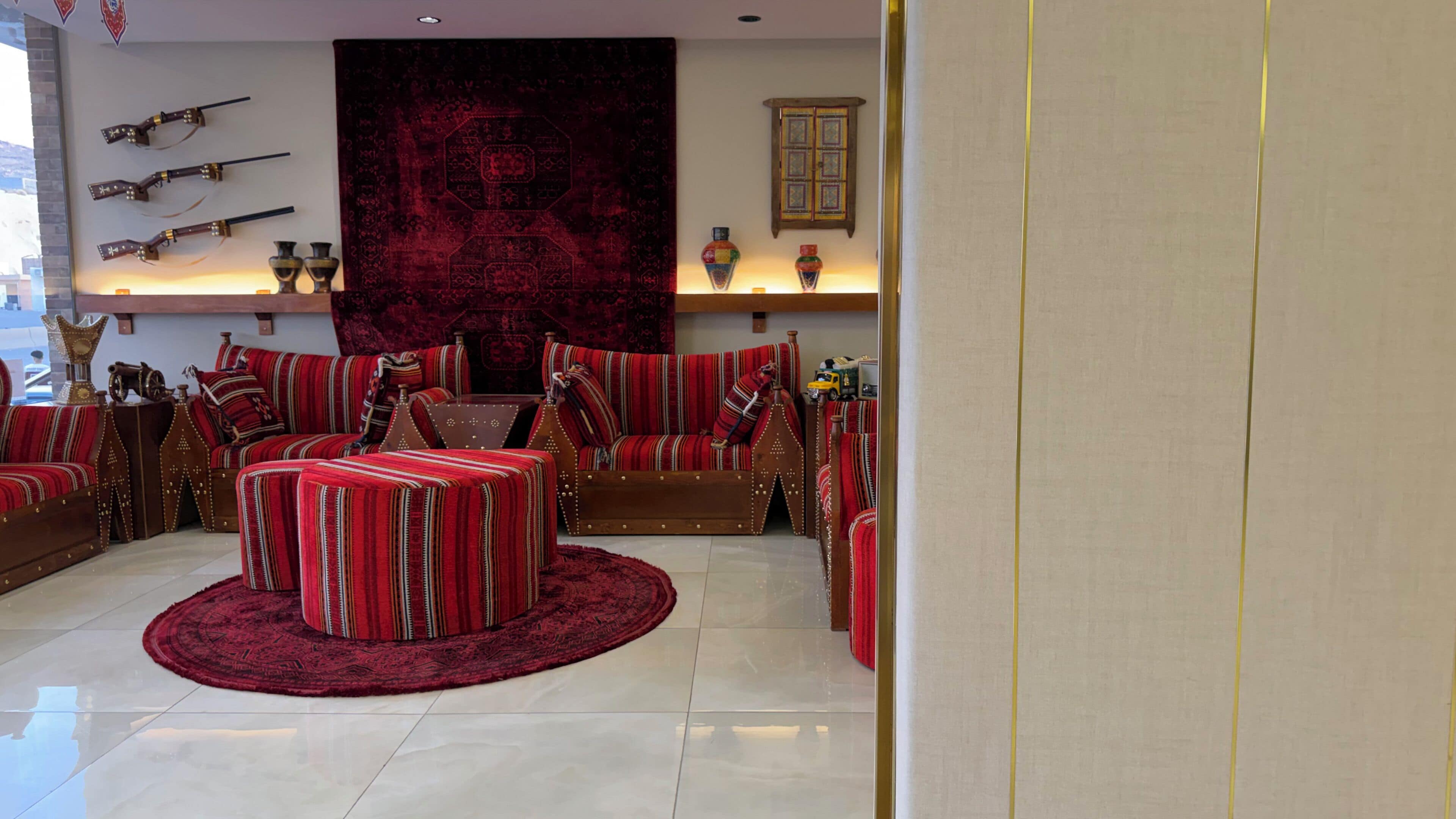 Una sala de estar con alfombra roja, sofás a rayas y un tapete grande rojo.