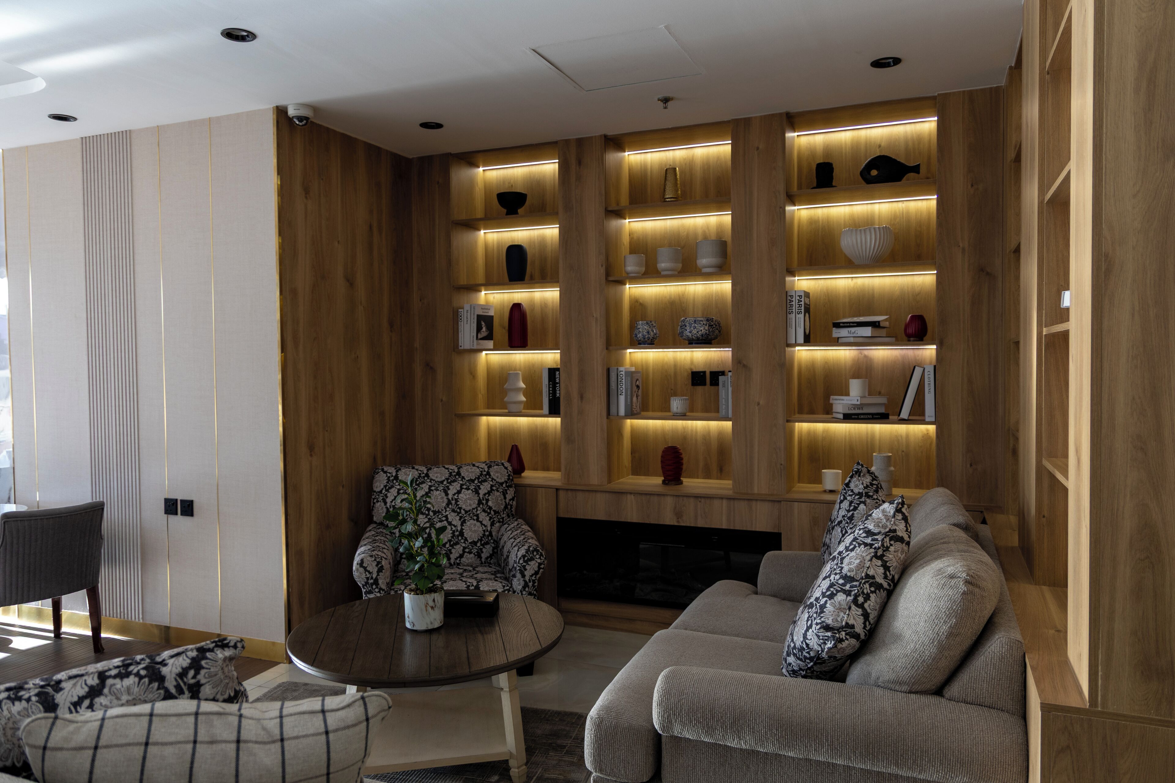 A modern living room with a wooden accent wall, a fireplace, and a sofa with decorative pillows.