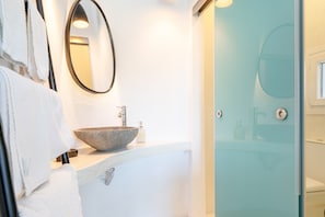 Une salle de bain avec un lavabo en pierre, un miroir et une cabine de douche en verre.
