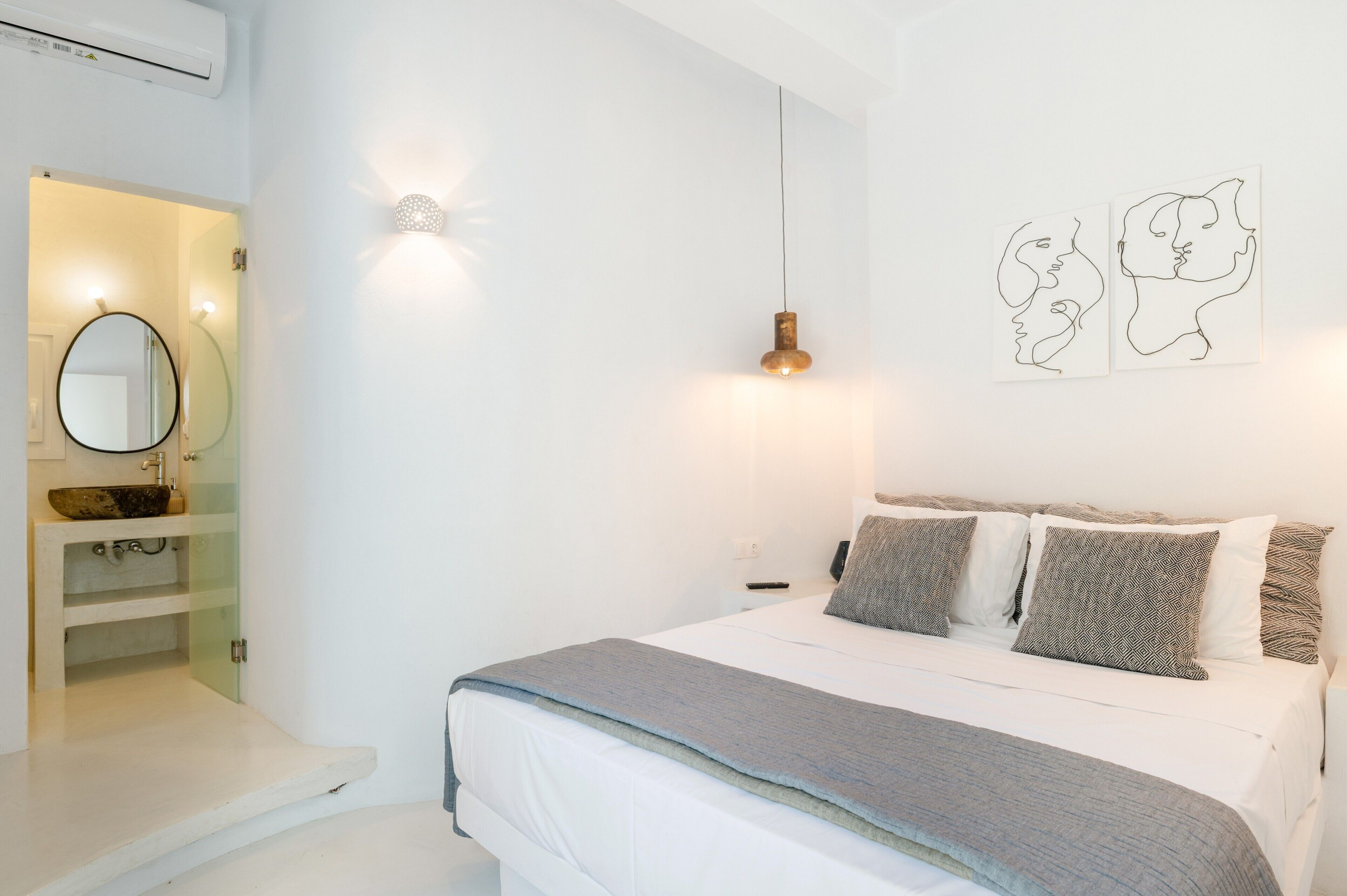 Un dormitorio con cama, mesita de noche, luz empotrada en la pared y un espejo.