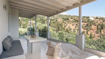 Una habitación moderna con un ventanal amplio, un sofá, una mesita y vistas a un paisaje montañoso.