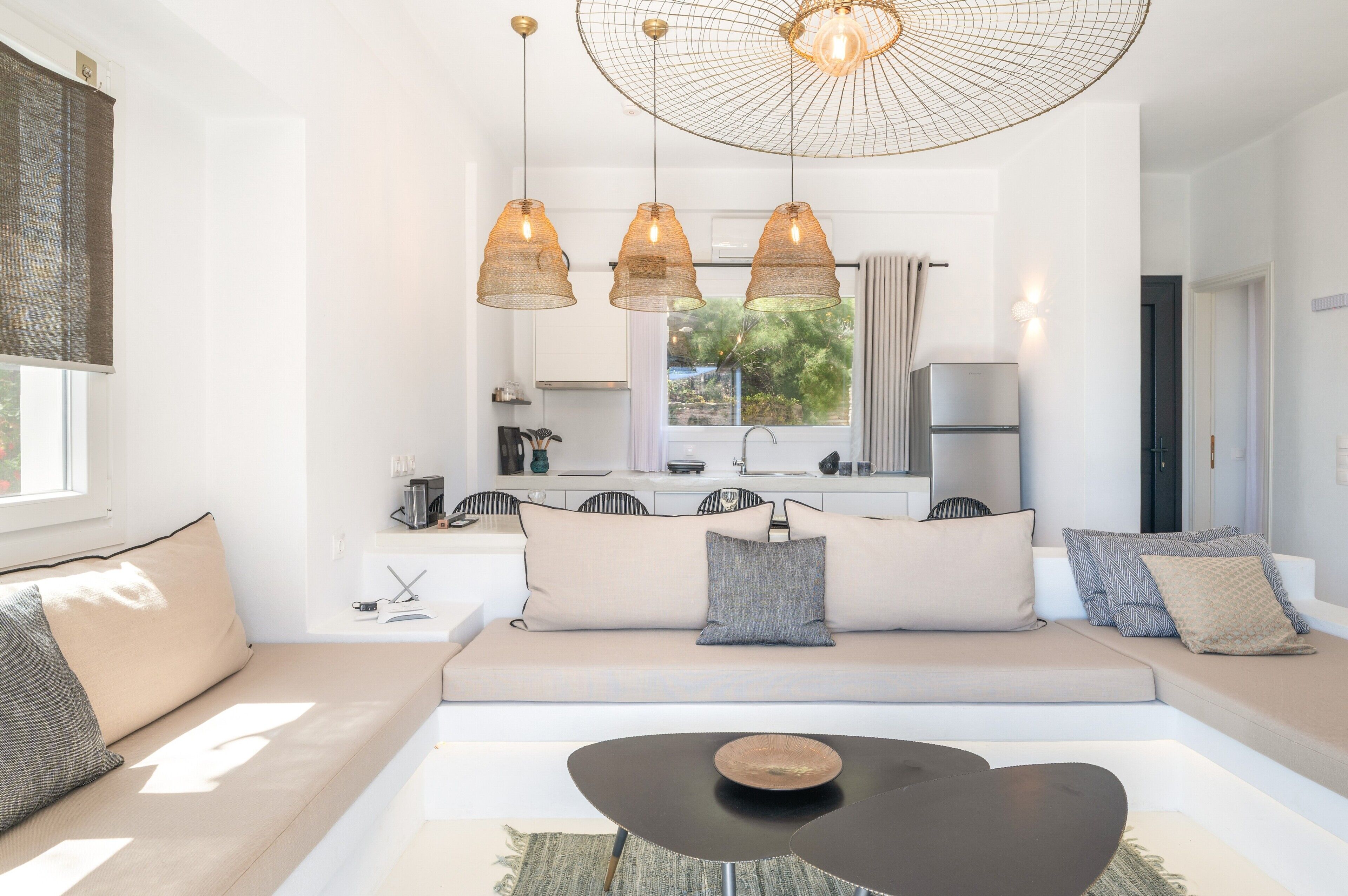 Una sala de estar moderna con un sofá, una mesa de centro, lámparas colgantes y vistas a la cocina.