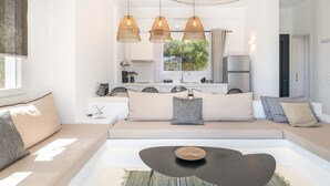 Una sala de estar moderna con un sofá, una mesa de centro, lámparas colgantes y vistas a la cocina.