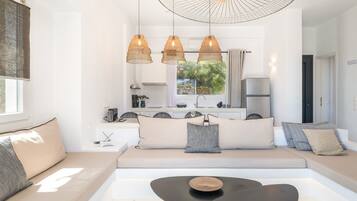 Una sala de estar moderna con un sofá, una mesa de centro, lámparas colgantes y vistas a la cocina.