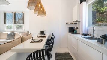 Una cocina moderna con comedor, armarios blancos y un ventanal grande.