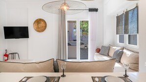 Una sala de estar moderna con comedor, televisor de pantalla plana y un ventanal con cortinas.