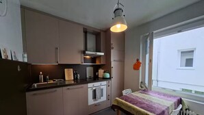 Eine kompakte Küche mit modernen Geräten, ein Essbereich mit Tisch und Stühlen sowie ein Fenster mit Blick nach außen.