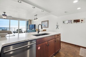 Una cucina moderna con un'isola grande, lavastoviglie in acciaio inossidabile, pensili in legno e vista all'esterno.