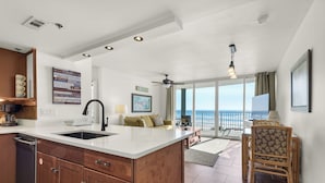 A spacious kitchen with a large island, a dining area with a view, and a balcony overlooking the ocean. - Beachfront front Condo with Stunning Views & Last-Minute August Discounts! (Panama City Beach)