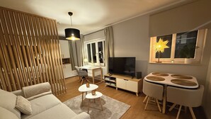 A modern living room with a sofa, a dining table, a TV, and a decorative star lamp. - Our new and cozy Krämernest in the old town, 100m to the Krämerbrücke (Erfurt)