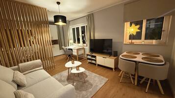 Ein modernes Wohnzimmer mit einer Couch, einem Esstisch, einem Fernseher und einer dekorativen Sternlampe.
