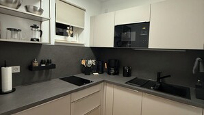 A modern kitchen with white cabinets, a black countertop, a built-in microwave, and a sink. - Our new and cozy Krämernest in the old town, 100m to the Krämerbrücke (Erfurt)
