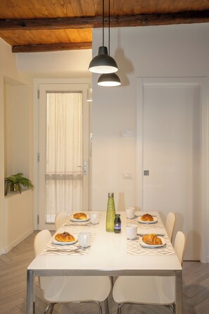 Un comedor con una mesa blanca, sillas y una lámpara colgante.