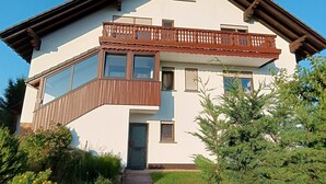 Una casa de dos pisos con balcón, ventanas amplias y una puerta.