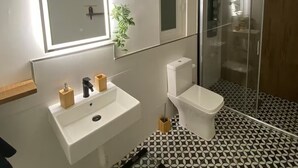Ein modernes Badezimmer mit Waschbecken, Toilette und Duschkabine aus Glas.