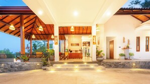 A hotel entrance with a covered porch, a reception desk, and steps leading to the main building. - River Shades Hotel (Hikkaduwa)