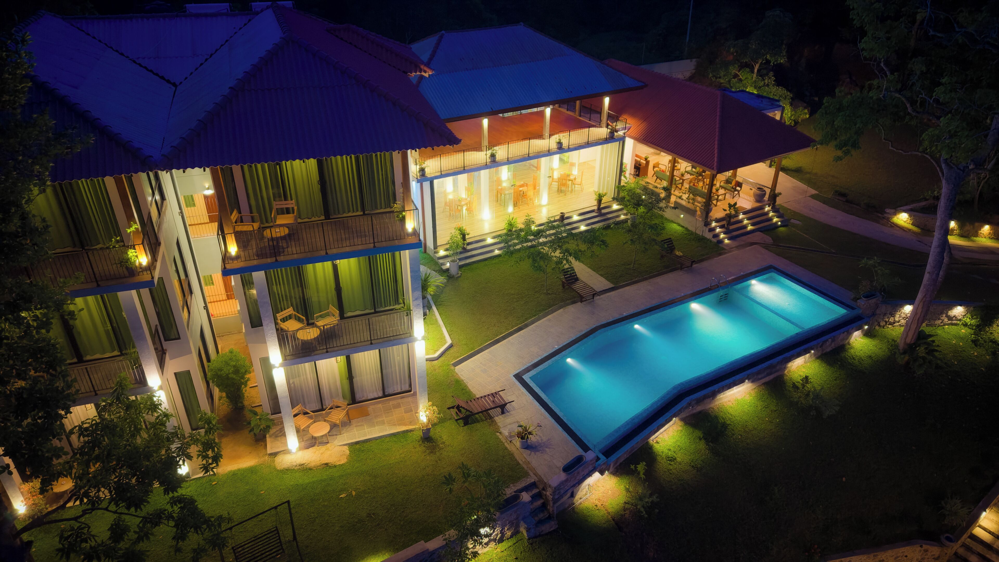 A two-story building with a swimming pool, outdoor seating, and a well-lit patio area.