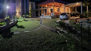 A modern house with a covered patio, a car parked in front, and a well-maintained lawn. - River Shades Hotel (Hikkaduwa)